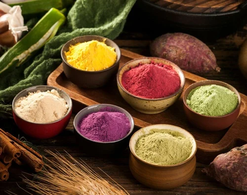 Small bowls filled with colourful dairy free powders surrounded by vegetables.